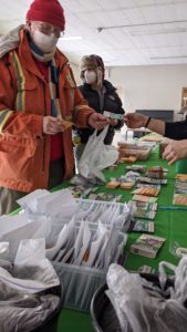 Envelopes on table with green tablecloth being handed to two participants at Seedy Saturday