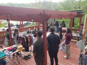 A group of young people stand on a deck among racks and tables of clothes