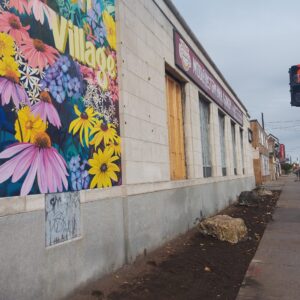A beautiful mural is on the wall and the concrete has been replaced with a garden bed.
