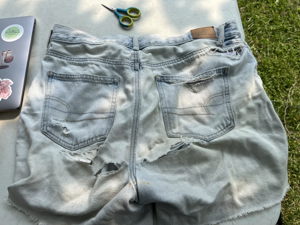[ID: Pale denim shorts with tears under the shorts and by the waistband] 