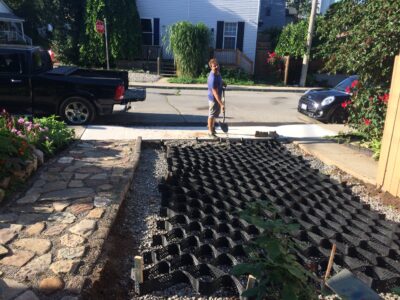 NATURhoods geogrid on driveway with a worker shoveling gravel in
