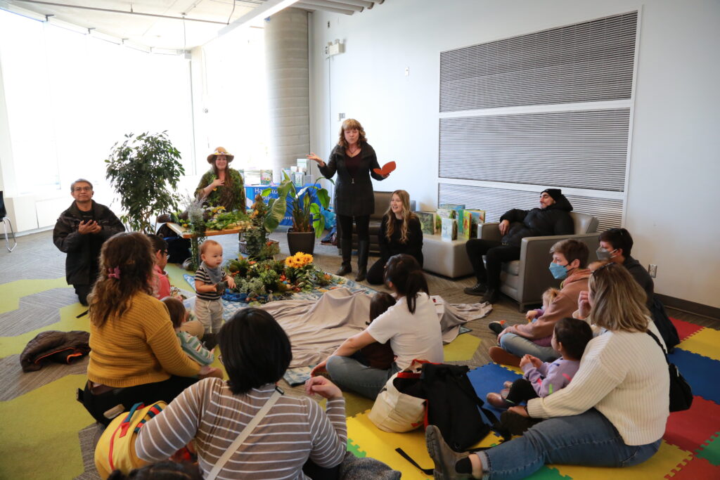 Jackie Ryan tells a story to a group of children and caregivers seated around her