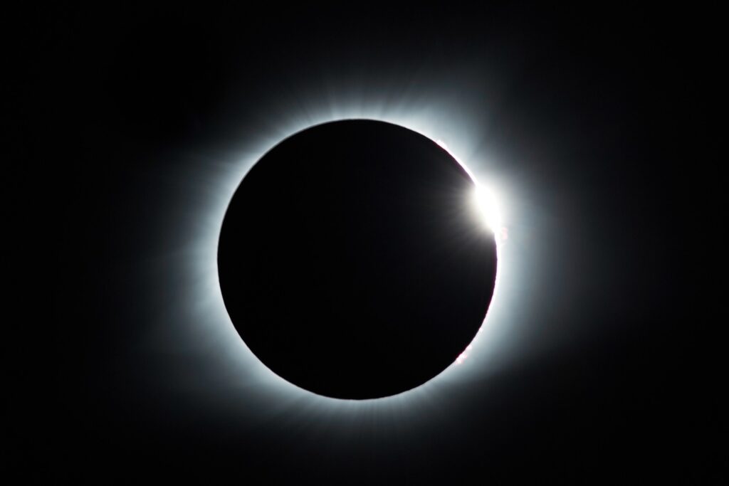 A fully eclipsed sun, just a glowing ring around the moon's shadow is shown against a dark sky